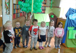 Zielone balony oraz dzieci recytujące wierszyk.